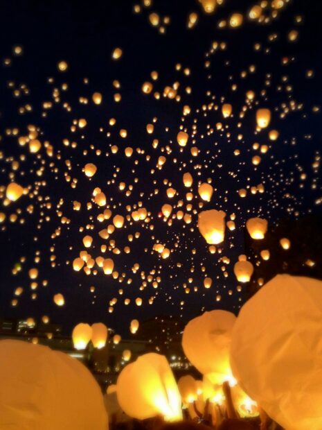 Glowing lanterns floating in the night sky during a festival celebration