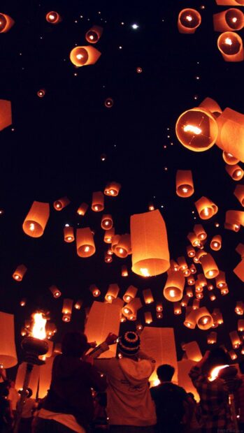 People releasing sky lanterns during festival night celebration
