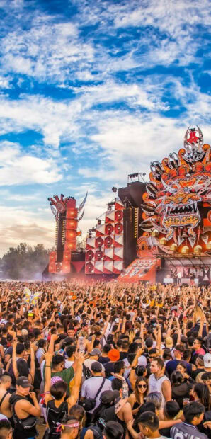 Large festival crowd enjoying music under a bright sky at an outdoor event
