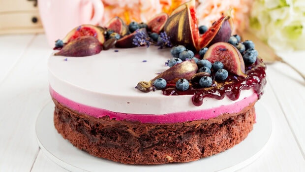 A delicious fig and blueberry topped cake with creamy layers on a white plate