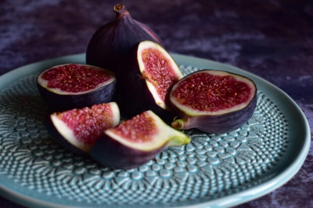 Fresh fig slices arranged on a decorative blue plate with textured patterns