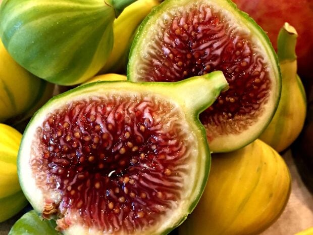 A close up view of fresh ripe fig showing its red pulp and seeds inside the green skin