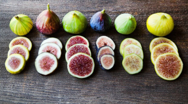 Fresh sliced fig fruits arranged neatly on wooden surface with various colors