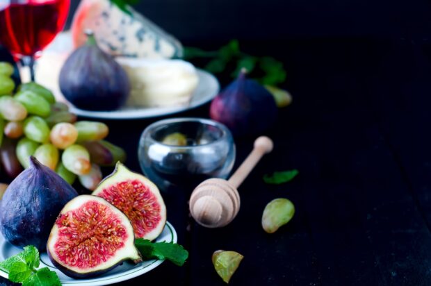 Fresh fig fruit halves on a plate with grapes and cheese in high definition