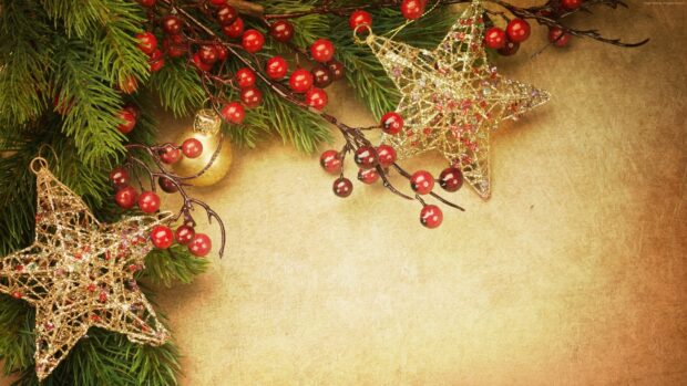 Fir tree branches with red berries and golden star decorations on a vintage background