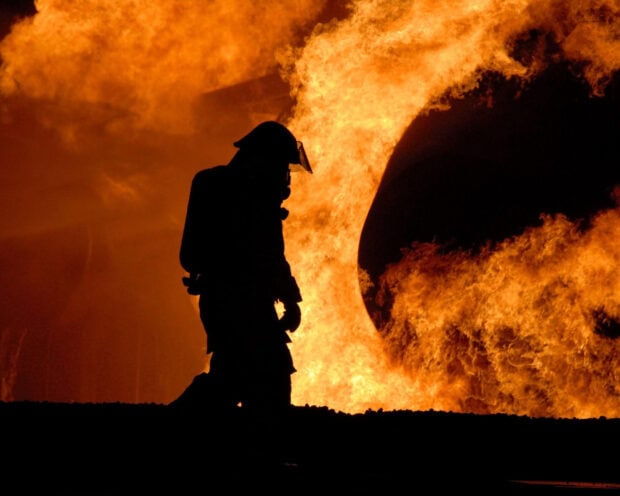 A fireman standing in front of intense flames during firefighting operation
