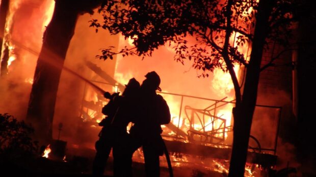 Fireman fighting fire with water hose in a blazing fire scene