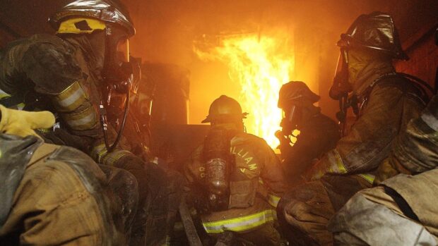Fireman in protective gear battling a large blaze inside a burning building