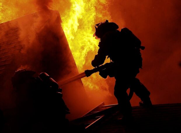 Fireman battling intense fire on a rooftop during night emergency