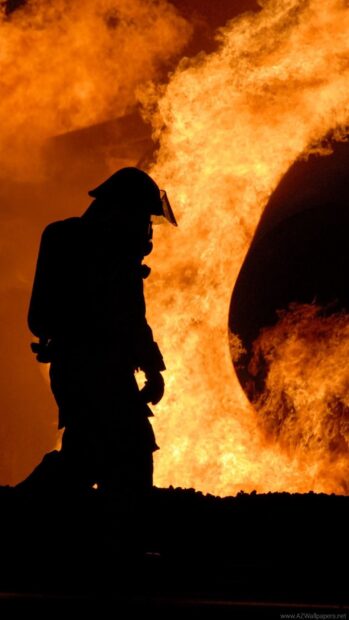 Fireman silhouette facing large fire flames during a night operation