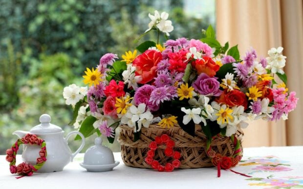 A vibrant flower bouquet with roses daisies and various blossoms in a wicker basket