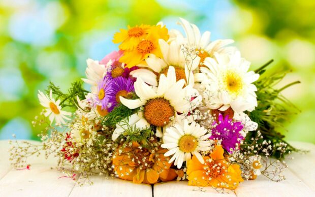 A colorful flower bouquet with daisies and wildflowers on a wooden surface