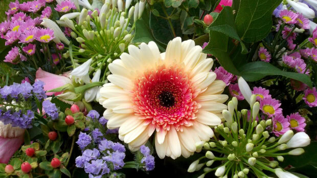 A vibrant flower bouquet featuring a large peach and pink gerbera surrounded by various colorful flowers
