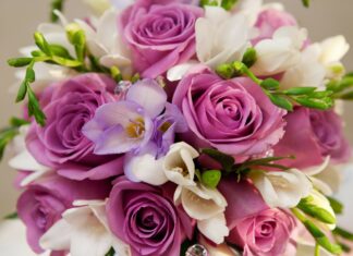 A vibrant flower bouquet with purple roses and white blossoms arranged beautifully