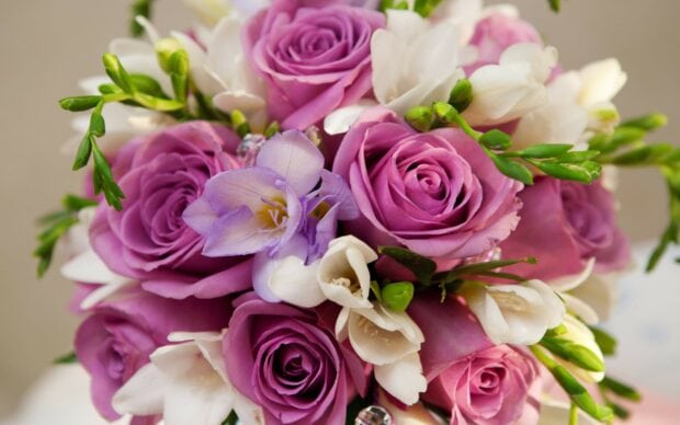 A vibrant flower bouquet with purple roses and white blossoms arranged beautifully