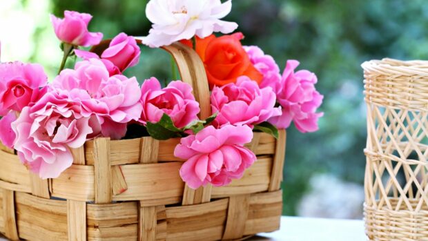 A vibrant flower bouquet with pink and orange roses arranged in a wooden basket
