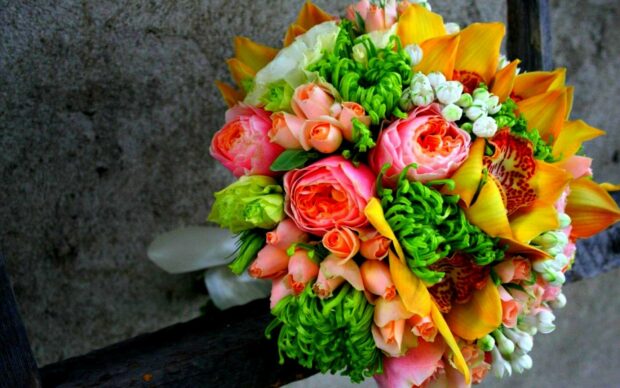 A vibrant flower bouquet with green chrysanthemums and peach roses on a dark background