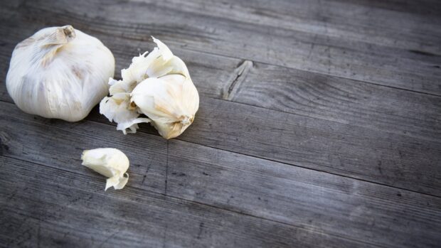 A close up of garlic cloves on a wooden surface with natural texture