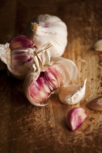 A close up of purple garlic cloves on a wooden surface