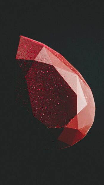 A close up of red gemstone with water droplets on its surface