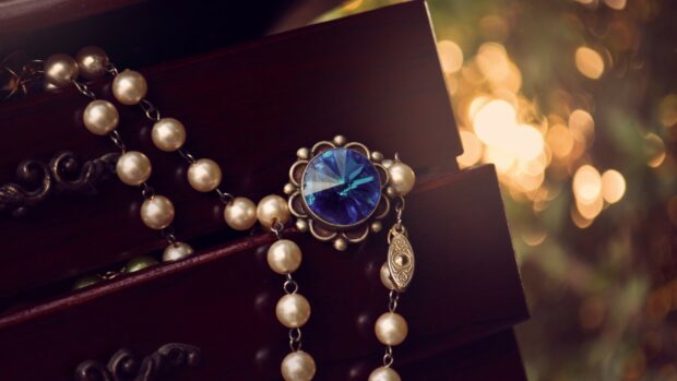 A close up of gemstone jewelry with pearls on a dark wooden surface