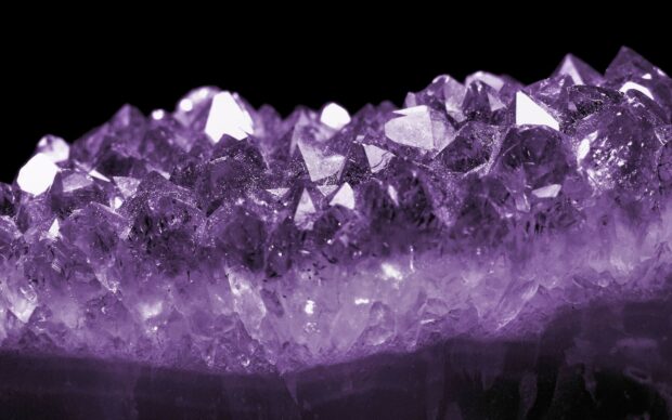Close up of a purple gemstone crystal cluster showing natural gemstone details