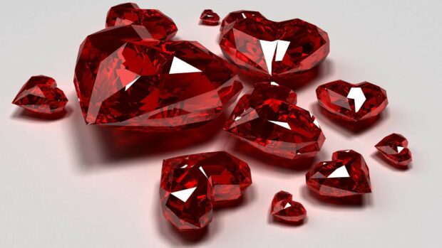 Shiny red gemstone hearts scattered on a smooth surface reflecting light