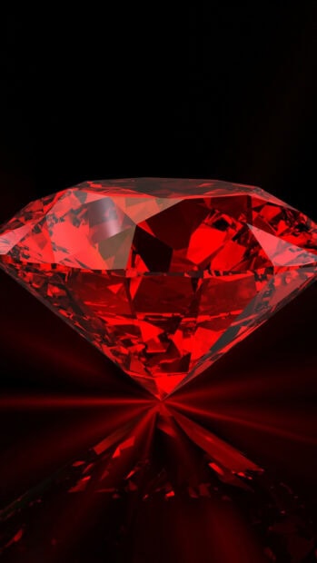 A close up of a red gemstone reflecting light on a dark surface