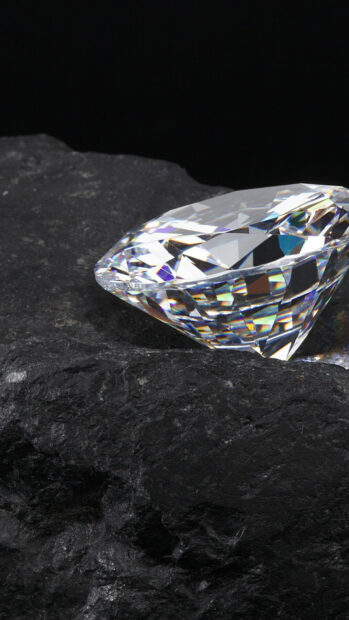 Clear gemstone resting on dark textured rock surface