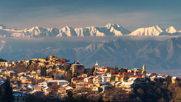 A scenic view of Georgia town with snow capped mountains in the background at sunset