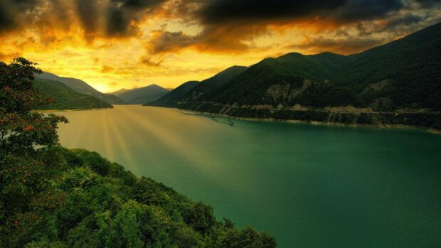 Golden sunset over Georgia river and lush green hills with a cloudy sky