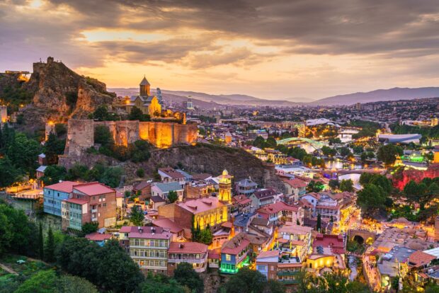 Historic Georgia cityscape with illuminated fortress and colorful buildings at sunset