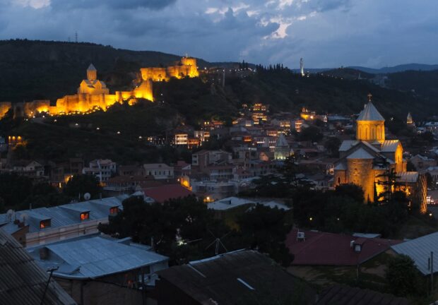 Night view of Georgia with illuminated ancient fortress and cityscape on hillside
