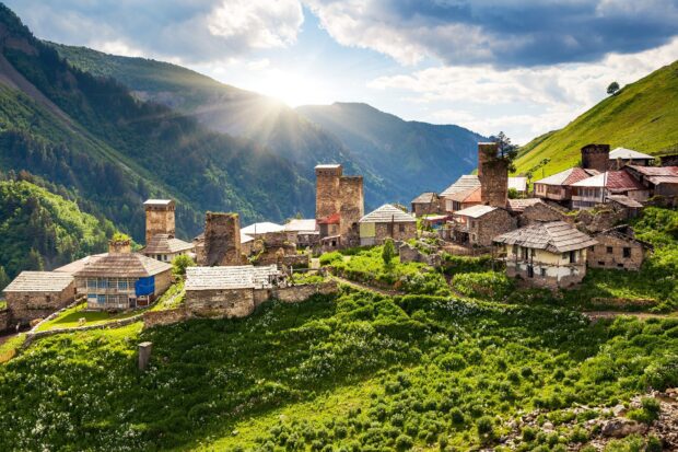 Traditional Georgian village with stone towers under sunlight in mountain landscape