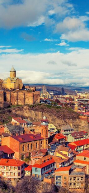 Historic buildings and fortress in Georgia city landscape under a blue sky