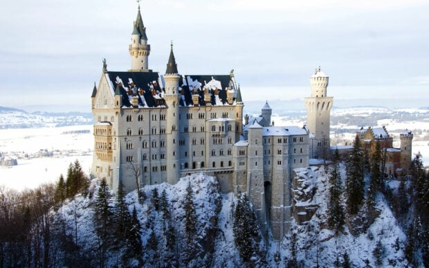 Neuschwanstein castle in Germany covered with snow during winter on a mountain ridge
