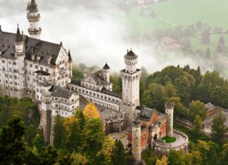 A stunning view of a historic castle in Germany surrounded by lush green forests and mist