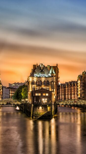 Historic architecture in Germany surrounded by water during sunset with glowing lights