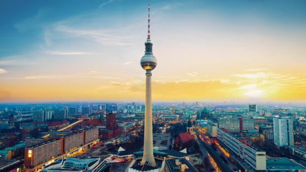 The Berlin TV tower dominates the cityscape of Germany at sunset with vibrant lights and clear skies