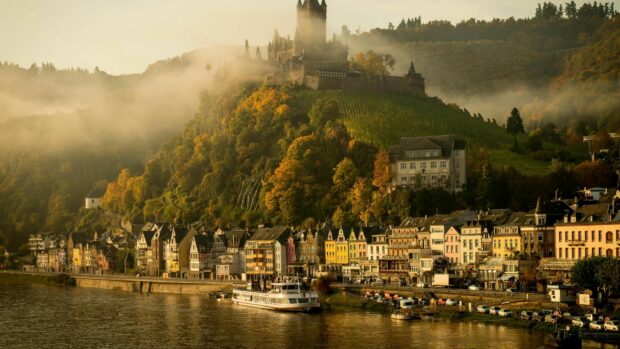 A scenic view of a Germany hillside town with colorful houses and historic castle surrounded by autumn trees