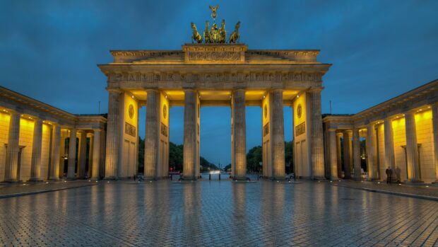 The iconic Brandenburg Gate in Germany illuminated at dusk with clear blue sky