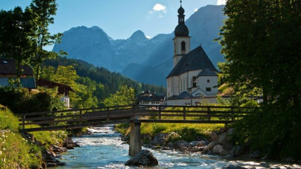 A peaceful village landscape with a church and mountains in Germany surrounded by lush greenery