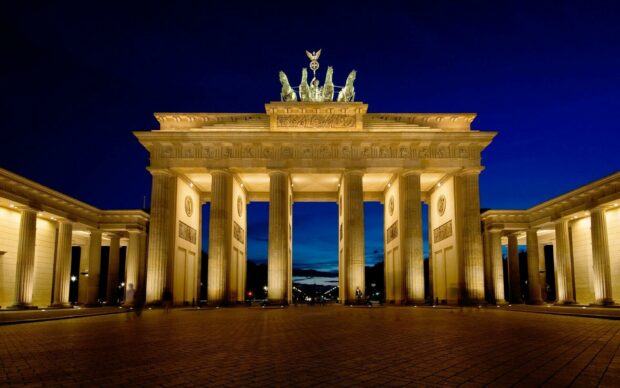 The Brandenburg Gate in Germany illuminated at night under a deep blue sky