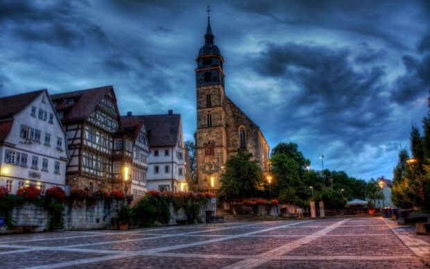 Historic architecture in Germany town square under dramatic sky with street lamps and flowers