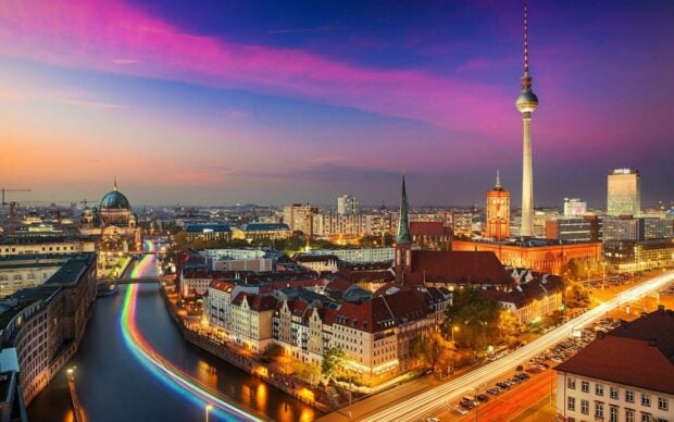 A beautiful cityscape of Germany showing historic buildings and a river at sunset with vibrant sky colors
