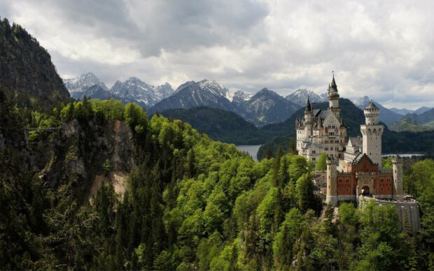 Neuschwanstein castle surrounded by green forest and mountains in Germany