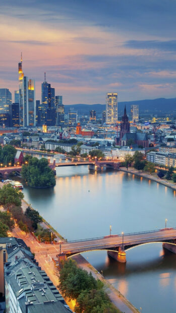 A beautiful cityscape of Germany featuring the river and modern buildings at sunset