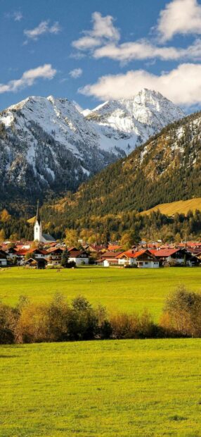 Snowy alpine mountains and green fields in Germany village Germany
