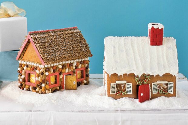 Two decorated gingerbread houses with various candies and icing on a snowy surface