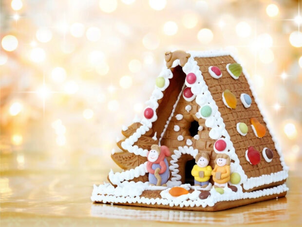 A detailed gingerbread house with icing and colorful candy decorations on a shiny surface